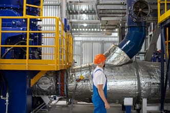 Profissional inspeciona um sistema pressurizado com isolamento térmico, em ambiente industrial.